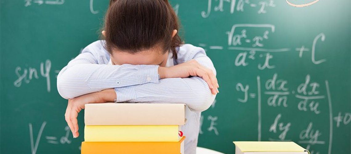 A student with her head down on a stack of books.